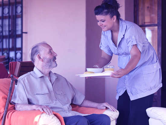 assistente per anziani in genova serve la colazione all'anziano che accudisce