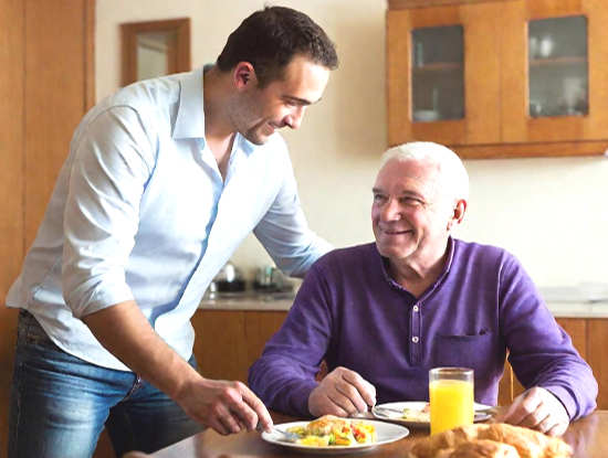 un caregiver domiciliare a imperia serve la colazione a un anziano